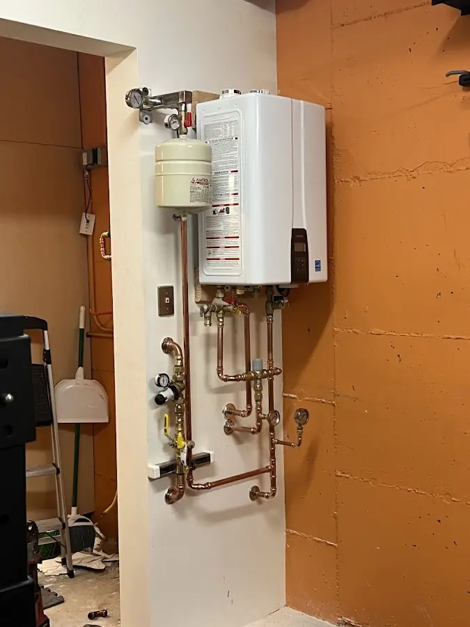 Plumbing technician inspecting water heater connections in Champlain
